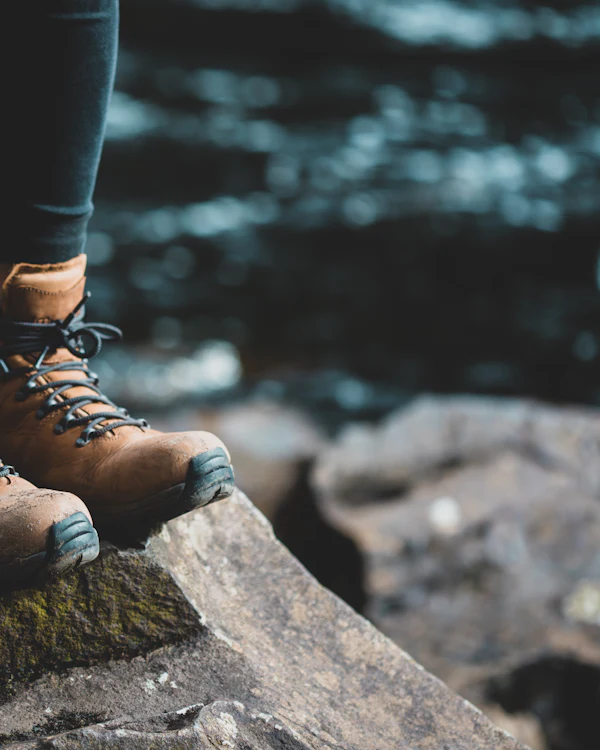 Getragene Wanderschuhe auf einem Felsen am Wasser